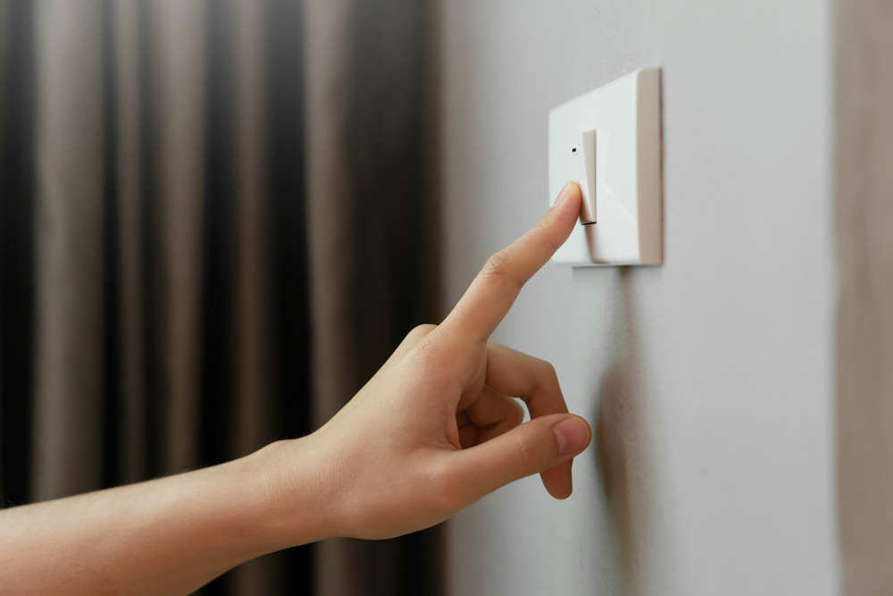 Close-up of a woman's hand pressing a light switch.