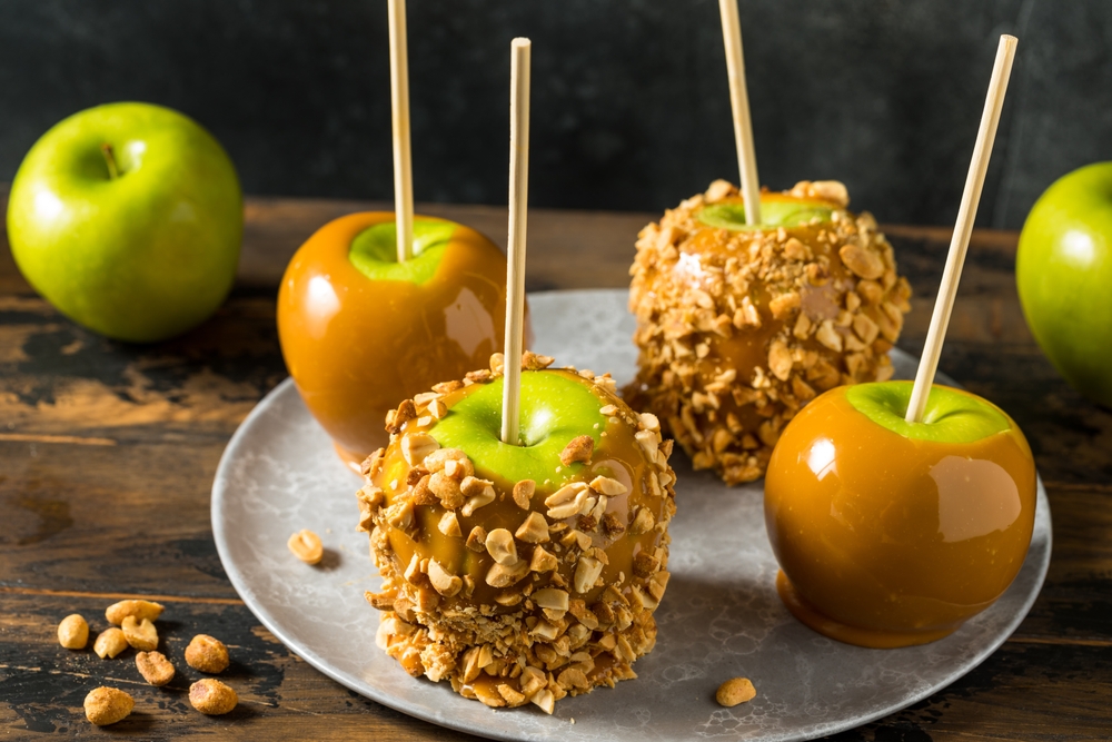 Close-up of caramel apples covered with chopped peanuts.