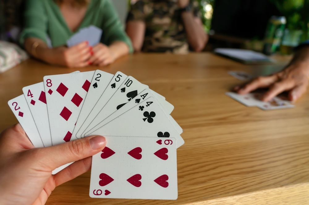 Close-up of a person holding cards and playing a card game.