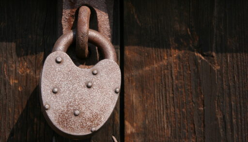 Old metal padlock on a wooden door.