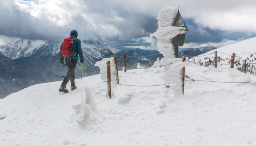Mountaineer walking along a mountain in Slovenia with a post covered in rime ice.