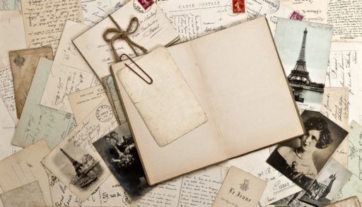 Empty scrapbook with old photos and letters laying around it.