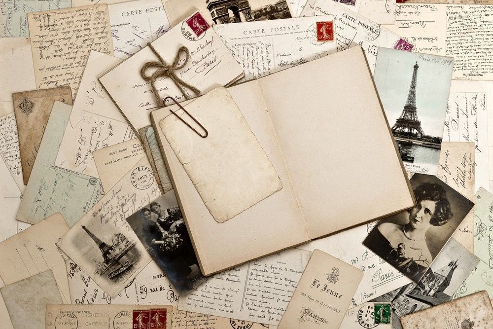 Empty scrapbook with old photos and letters laying around it.