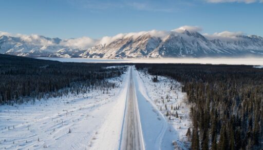 Aerial view of a road cutting through a snowy forest in Whitehorse, Yukon.