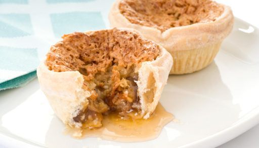Two butter tarts on a white plate with a runny filling.
