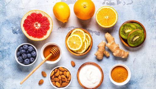 Flat lay of different immune system-boosting foods, such as oranges, ginger and honey.