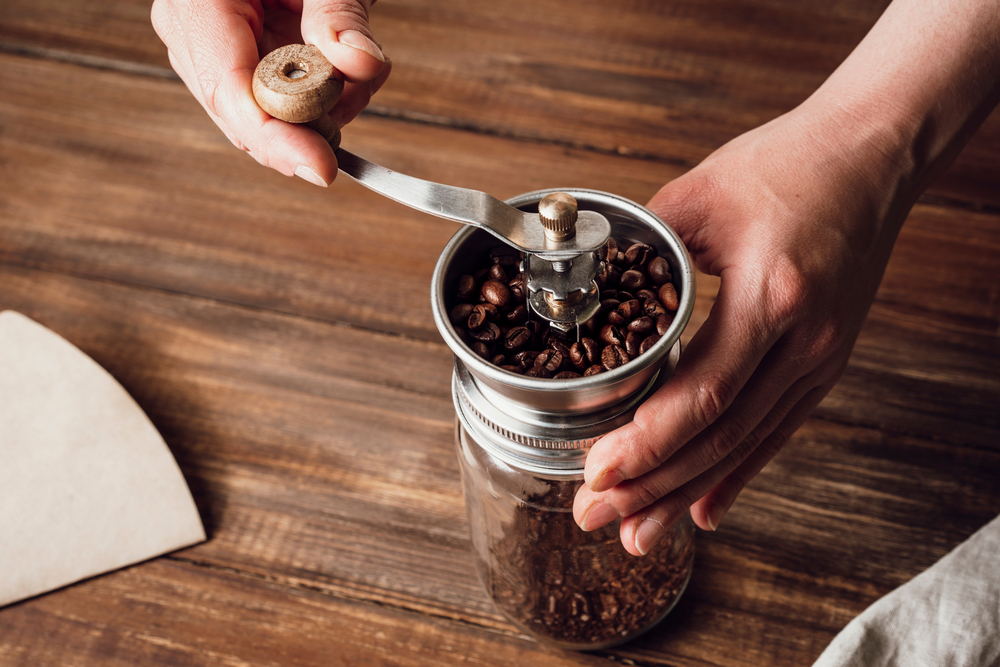 Close-up of a person using a coffee grinder to grind coffee beans.