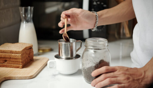 Close-up of a person spooning coffee beans into a filter.