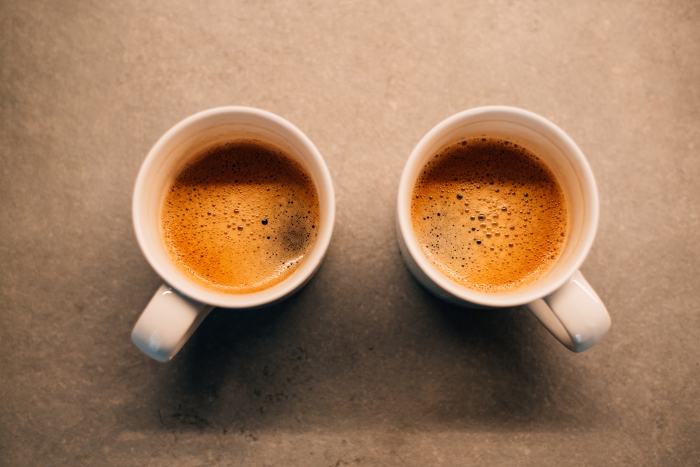 Overhead view of two white mugs filled with coffee.