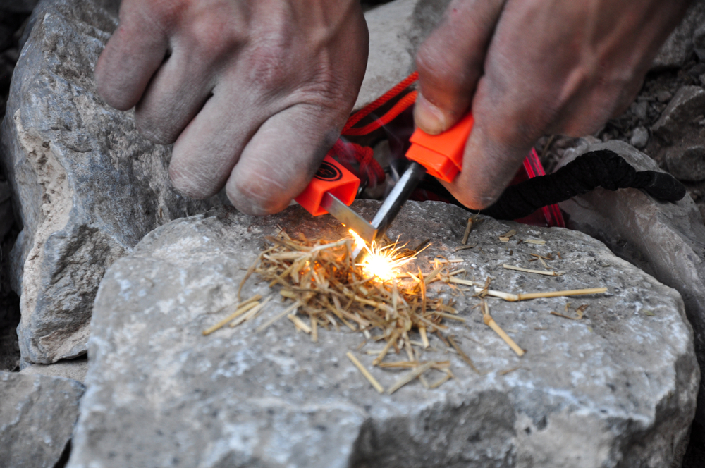 Close-up of a person using a fire starter to start a fire.