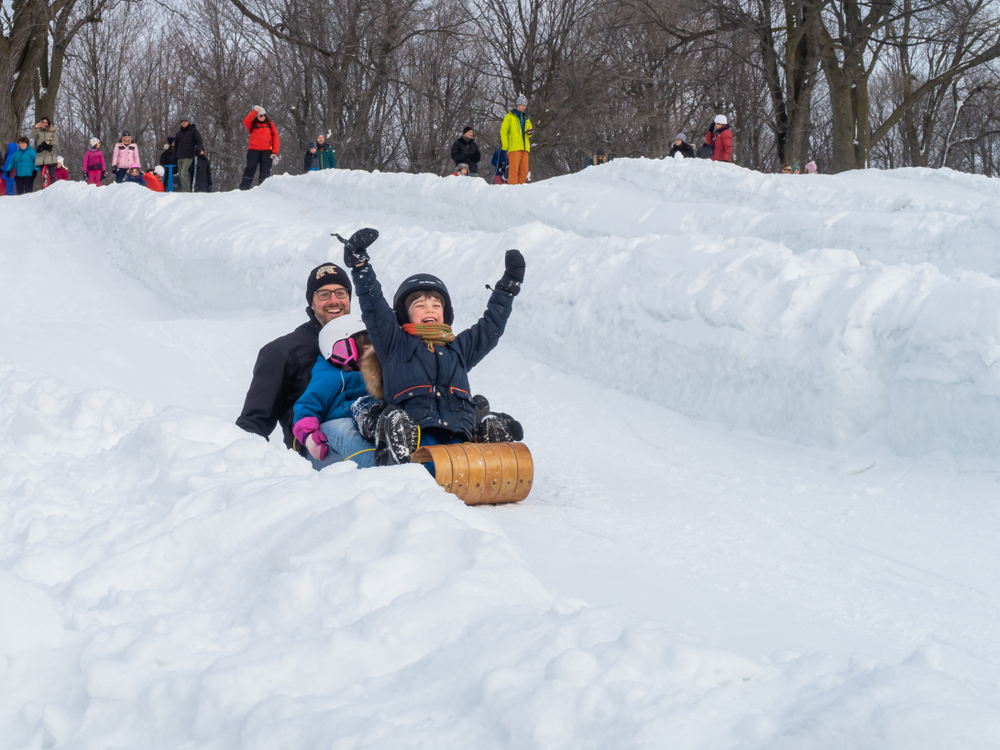 Man and children on a sled going down a hill