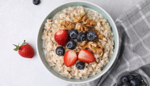 Overhead view of a bowl of oatmeal topped with blueberries, strawberries and walnuts.