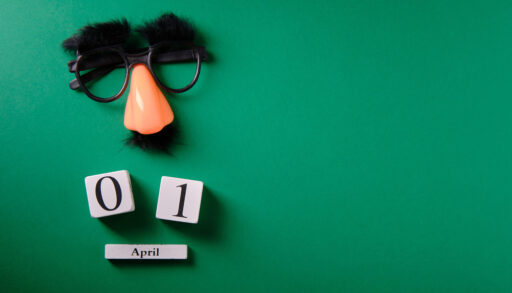 Fake mustache and glasses with blocks showing the date for April Fool's Day.
