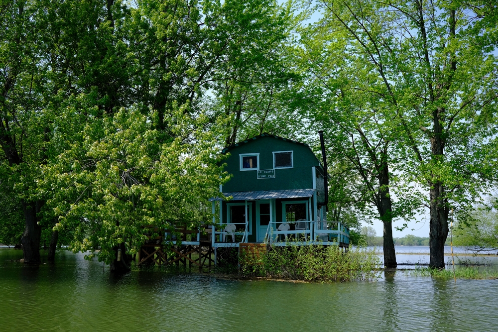 Green cottage on stilts during spring flooding in Sorel, Quebec.