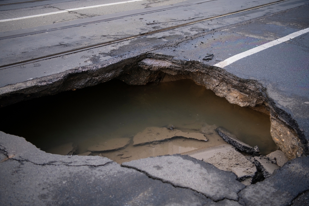 Close-up of a large sinkhole in a road.