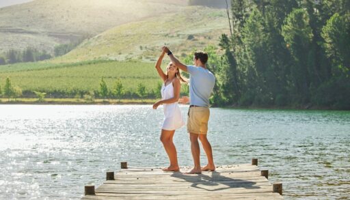 Young couple dancing on a lake dock.