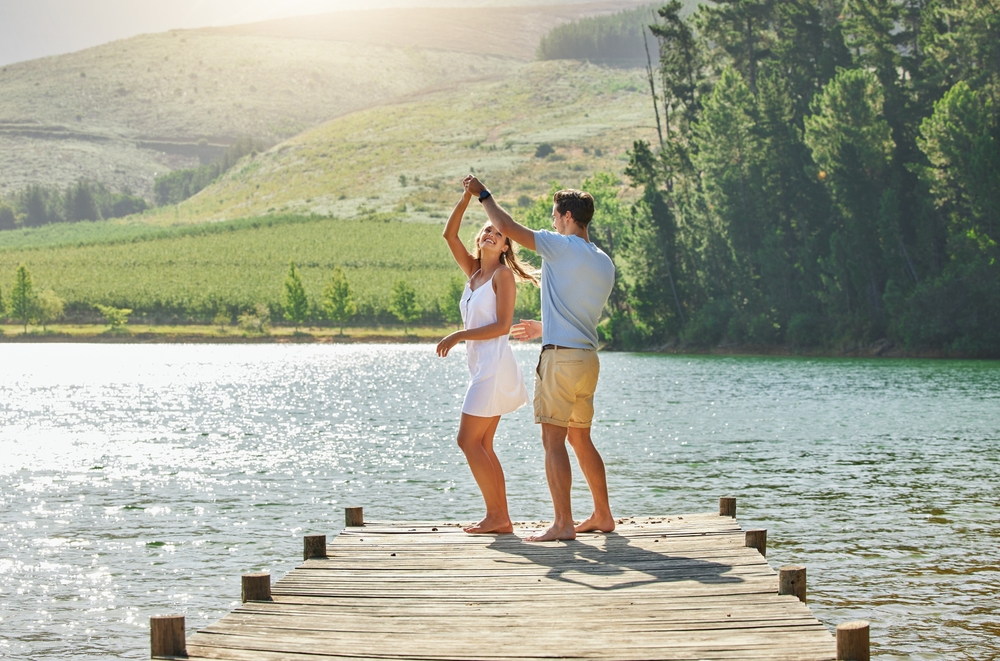 Young couple dancing on a lake dock.