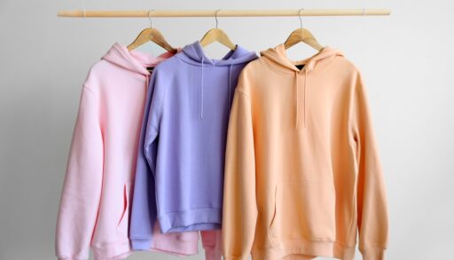 Pink, purple and orange hoodies hanging on a clothing rack.