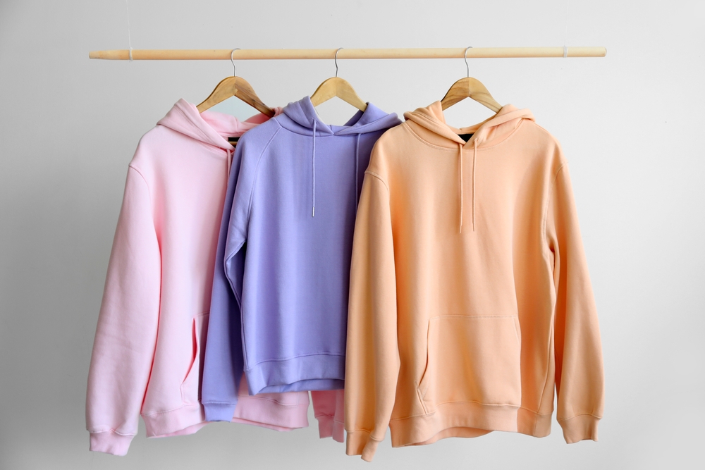 Pink, purple and orange hoodies hanging on a clothing rack.