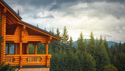 Log cabin overlooking a forest with a mountain in the background.