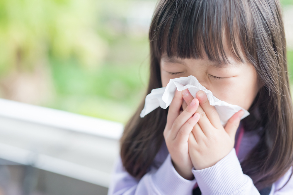 Close-up of a little girl blowing her nose.