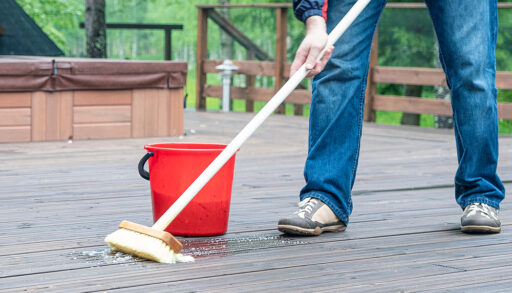 View of a man's feet and a broom and bucket as he washes his deck.