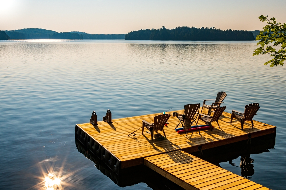 Wooden dock on a lake with Muskoka chairs.