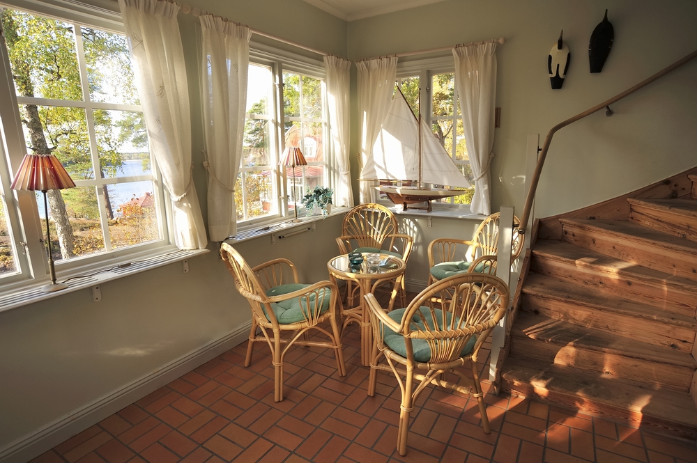 Small dining table with chairs in a cottage with sheer window coverings.