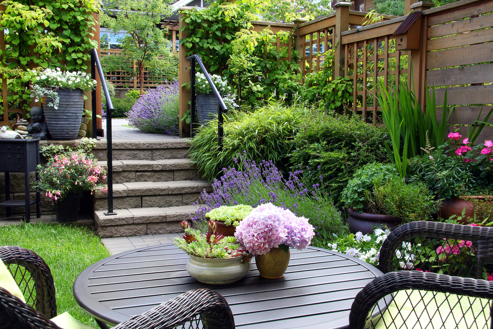 Small garden with patio furniture and pink flowers.