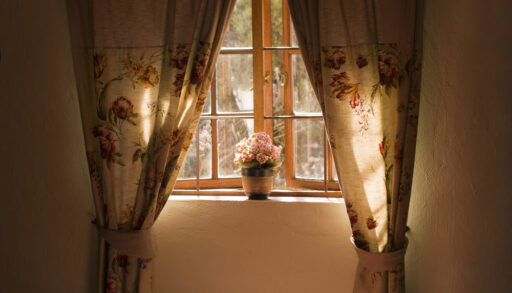 Wooden window with rustic curtains and a flower pot.