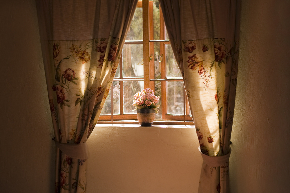 Wooden window with rustic curtains and a flower pot.