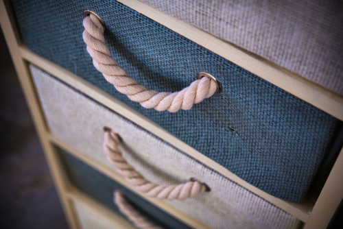 Close-up of rope handles on a blue and white chest of drawers.