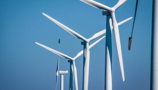 Close-up of white wind turbines against a clear blue sky.