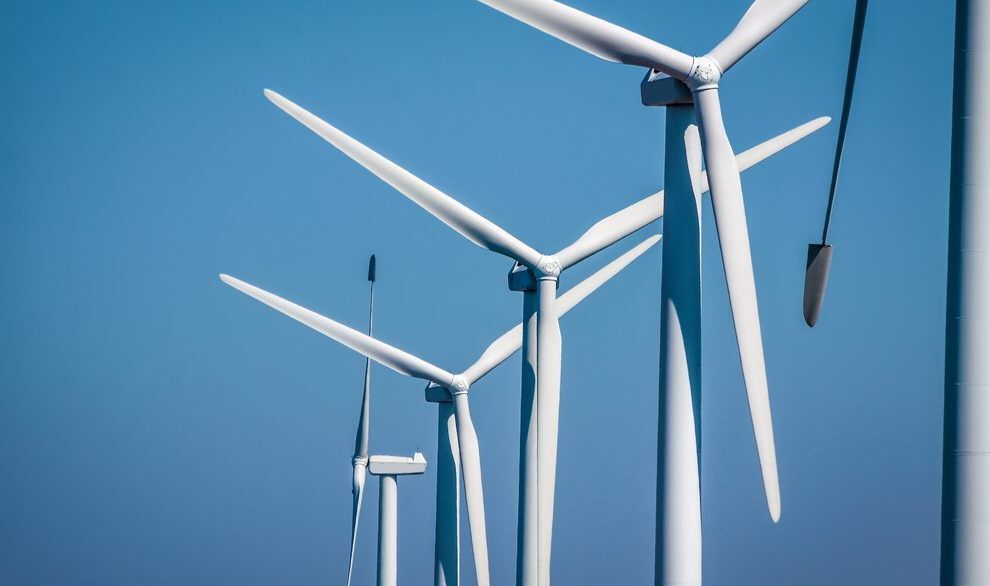 Close-up of white wind turbines against a clear blue sky.