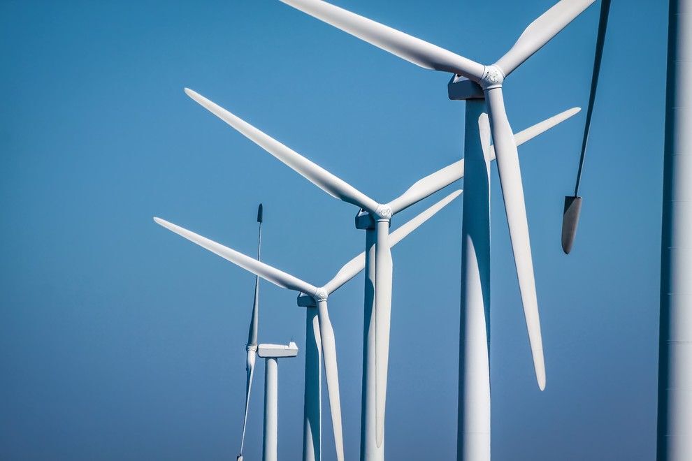Close-up of white wind turbines against a clear blue sky.