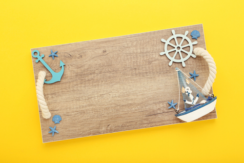 Wooden board with a blue ship and anchor on a yellow background.