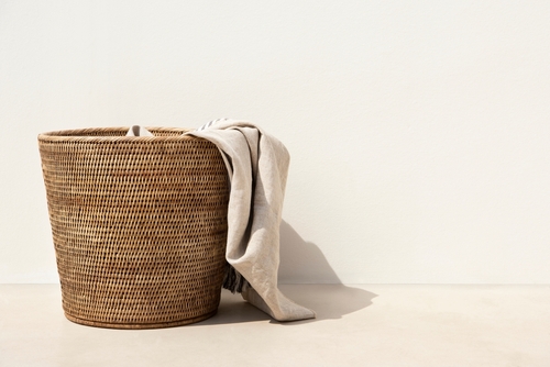 Woven wastebasket with a towel hanging out.