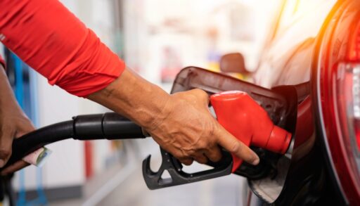 Close-up of a person using a red gas nozzle to refuel their car.