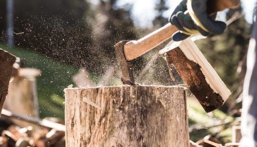 Close-up of an axe chopping a wood stump.