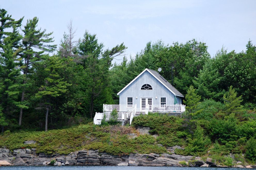 Cottage on a rocky shore surrounded by trees.