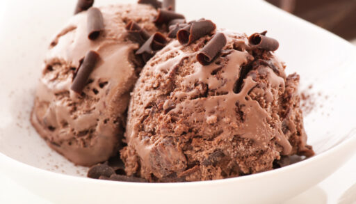 Close-up of two scoops of chocolate ice cream toped with chocolate curls.