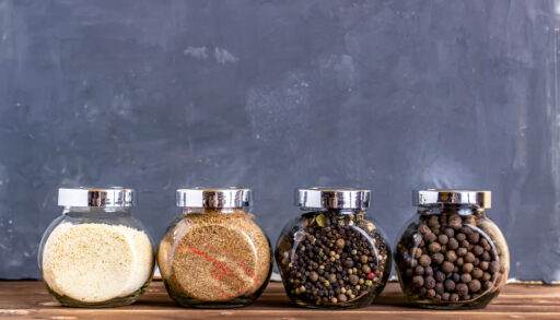 Four small, glass containers with different spices inside.