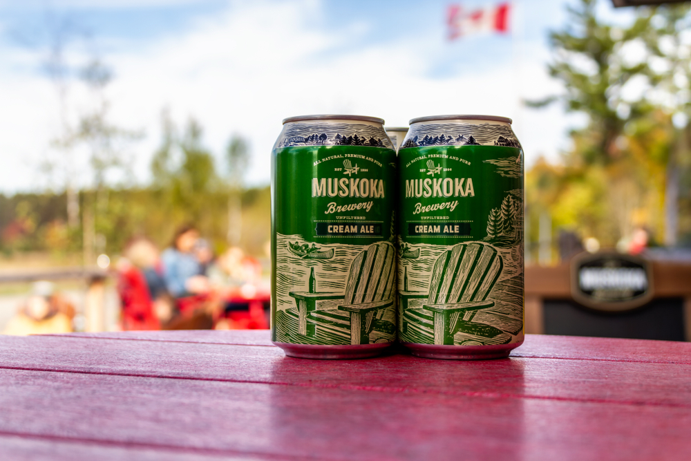 Close-up of two green beer cans from the Muskoka Brewery sitting on a red table.