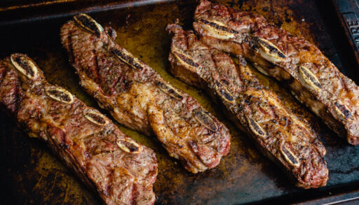 Grilled flanken ribs on a metal sheet pan.