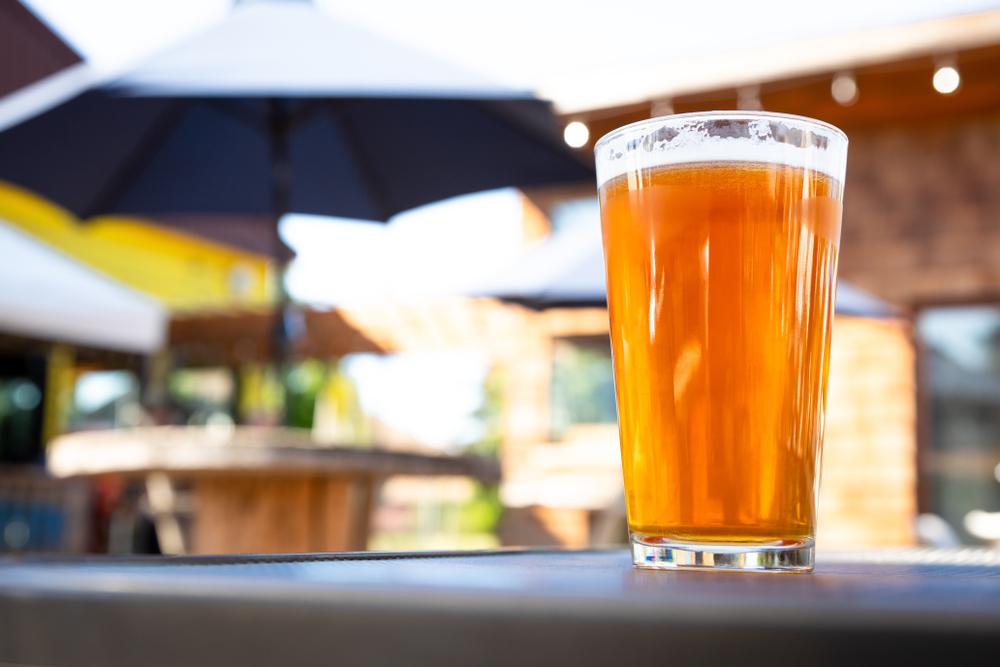 Close-up of a pint glass filled with beer on a patio table.