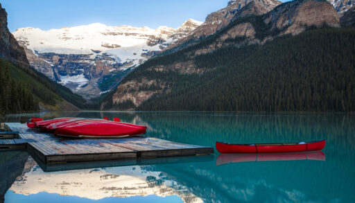 Row of red canoes on a turquoise lake in Banff National Park, Alberta.