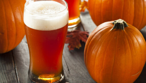 Glass of orange pumpkin beer next to a pumpkin.