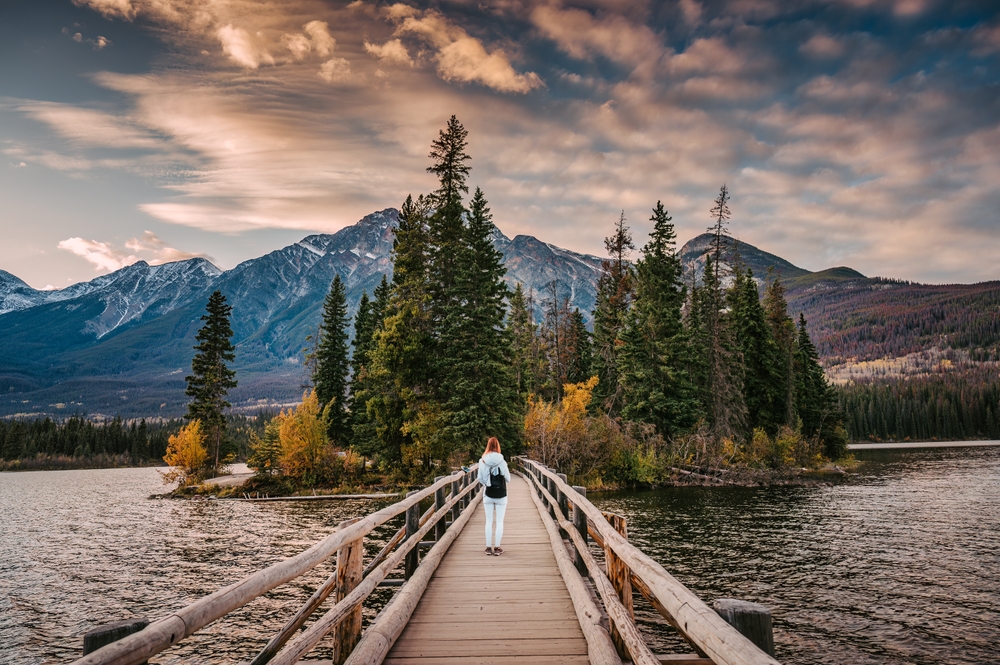 Woman standing on a bridge leading to Pyramid Island in Jasper National Park in autumn.