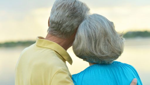 Retired couple standing looking at a lake.