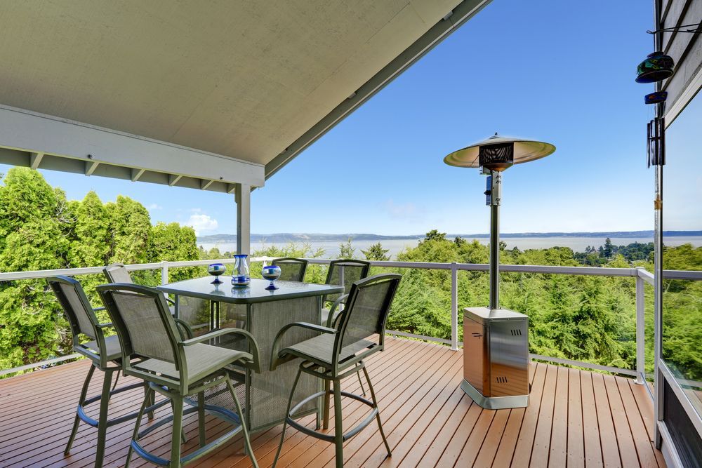 Patio area with table, chairs and heater on walkout deck overlooking scenic view